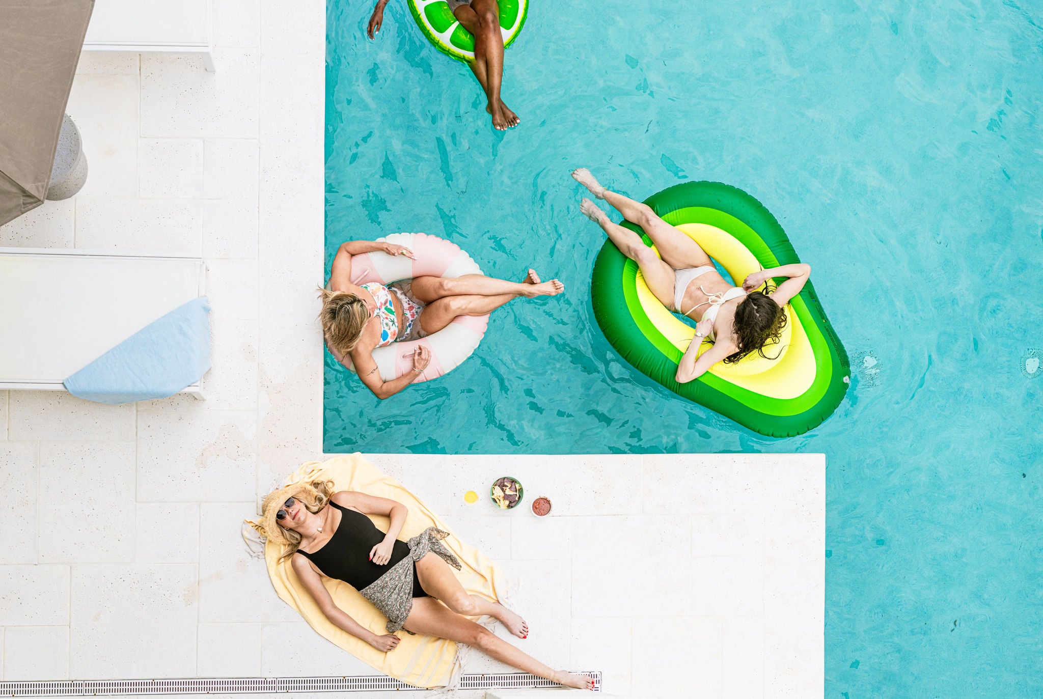 Ladies laying on floaties around a fabulous pool near the beach. 