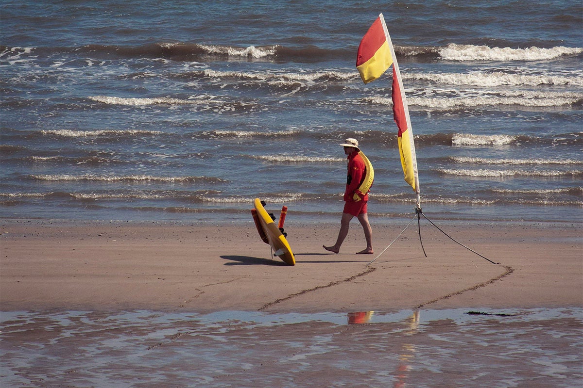 A lifeguard walks the beach. 