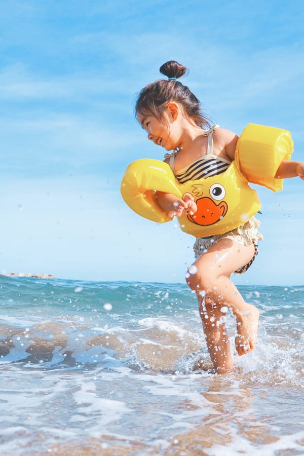 toddler with floaties playing in ocean